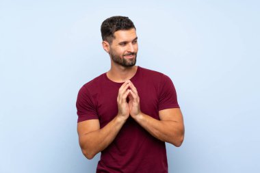 Yakışıklı bir adam, izole edilmiş mavi arka plan entrikaları çeviriyor.
