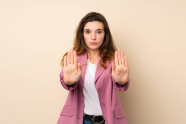 Spor ceketli genç esmer kız izole edilmiş arka planda dur hareketi yapıyor ve hayal kırıklığına uğruyor.