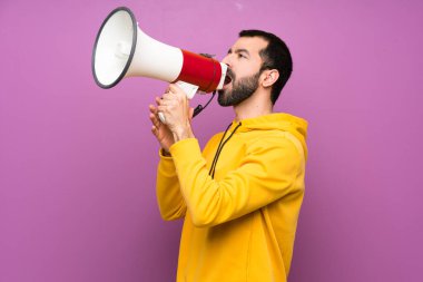 Sarı sweatshirt ile yakışıklı adam bir megafon ile bağırıyor