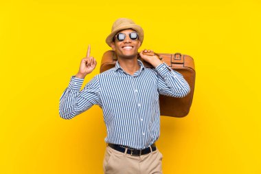 Esmer adam, izole edilmiş sarı arka plan üzerinde klasik bir evrak çantası tutuyor. Harika bir fikre işaret ediyor.