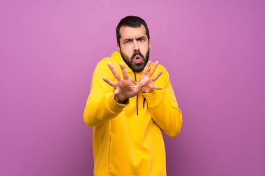 Sarı kazaklı yakışıklı adam ellerini öne uzatıyor.