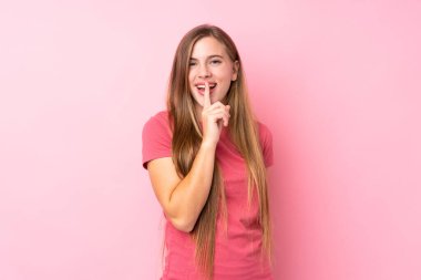 Soyutlanmış pembe arka planda genç sarışın kız sessizlik hareketi yapıyor.