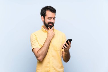 Sakallı genç bir adam mavi bir geçmişi var. Düşünüyor ve mesaj gönderiyor.