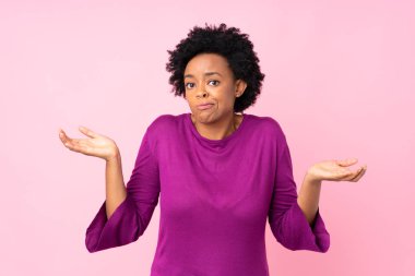 Afro-Amerikalı kadın pembe arka planda, elini kaldırırken şüpheye düşüyor.