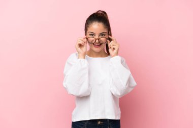 Genç esmer kız pembe arka planda gözlüklü ve şaşırmış.