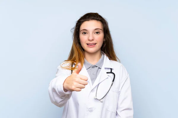 Doktor Elbisesi Başparmağıyla Soyutlanmış Mavi Arka Planda Genç Esmer Kız — Stok fotoğraf