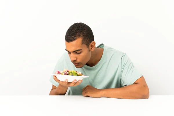 Ung stilig man med sallad i ett bord — Stockfoto