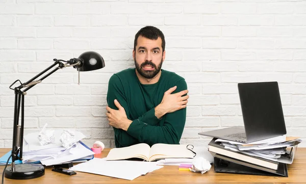 Student man freezing sitting at the table