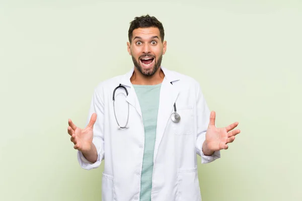 Ung Læge Mand Isoleret Grøn Væg Med Overraskelse Ansigtsudtryk - Stock-foto