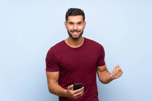 Stilig Man Över Isolerad Blå Bakgrund Med Telefon Seger Position — Stockfoto