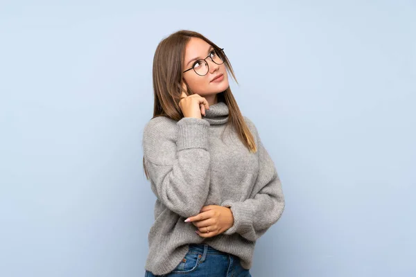 Menina Adolescente Com Suéter Sobre Fundo Azul Isolado Com Óculos — Fotografia de Stock