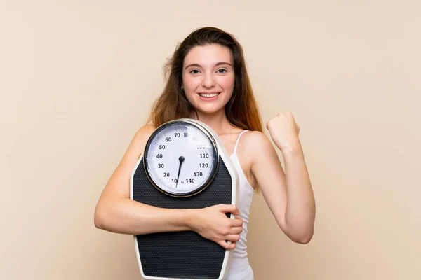 Young brunette girl  with weighing machine over isolated background