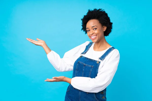 Mulher Afro Americana Com Macacão Sobre Fundo Azul Isolado Estendendo — Fotografia de Stock