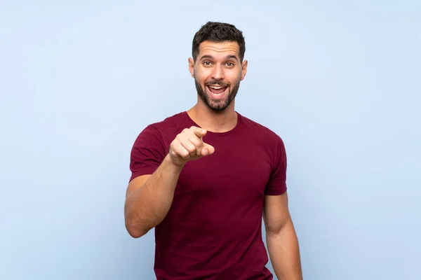 Hombre Guapo Sobre Fondo Azul Aislado Sorprendido Apuntando Hacia Delante — Foto de Stock