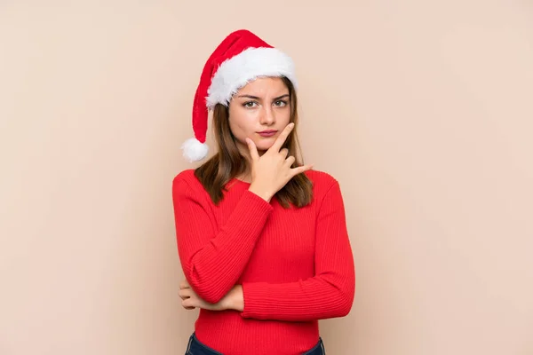 Young girl with christmas hat over isolated background thinking an idea