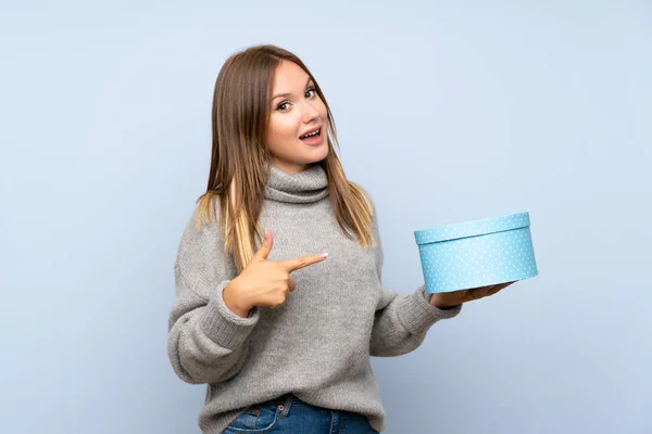 Menina Adolescente Com Suéter Sobre Fundo Azul Isolado Segurando Caixa — Fotografia de Stock