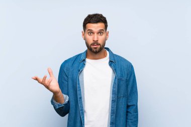 Soyutlanmış mavi arka planda yakışıklı bir adam şüpheli hareketler yapıyor.