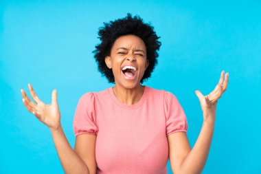 İzole edilmiş mavi arka plan üzerinde yaşayan Afro-Amerikalı bir kadın mutsuz ve hayal kırıklığına uğramış.