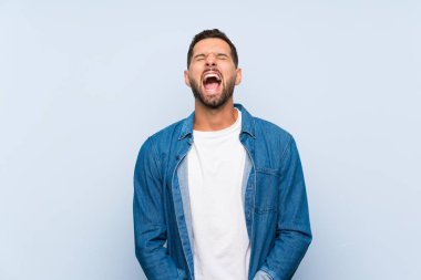 Ağzı tamamen açık ön bağırarak izole mavi arka plan üzerinde Yakışıklı adam