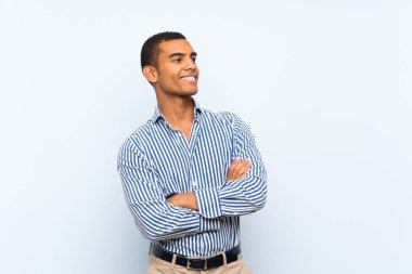 Genç, yakışıklı esmer adam mavi arka planda mutlu ve gülümsüyor.