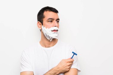 Adam sakalını soyutlanmış beyaz arka plan portresi üzerinde tıraş ediyor.