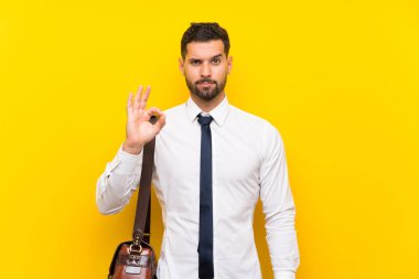 İzole edilmiş sarı arka planda yakışıklı iş adamı parmaklarıyla 