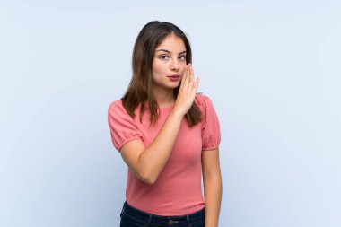 Genç esmer kız izole edilmiş mavi arka planda bir şeyler fısıldıyor