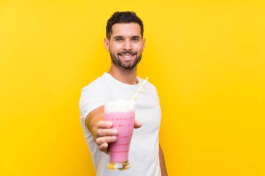 Izole sarı arka plan üzerinde çilek milkshake ile genç adam