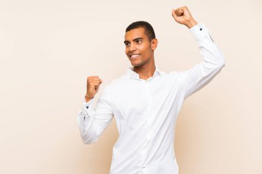 Genç, yakışıklı, esmer adam izole bir arka planda zaferi kutluyor.