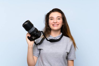 Genç esmer kız izole edilmiş mavi arka planda profesyonel bir kamerayla