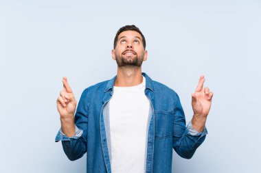 Parmakları geçiş ve en iyi dilek ile izole mavi arka plan üzerinde Yakışıklı adam