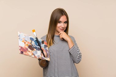 Genç kız izole arka plan gülerek üzerinde bir palet tutan