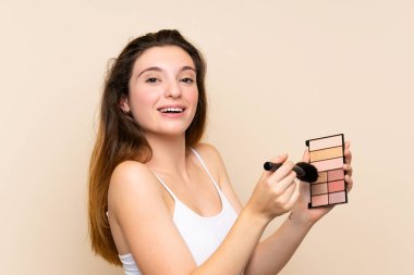 Soyutlanmış arka planda makyaj paleti olan esmer bir kız.