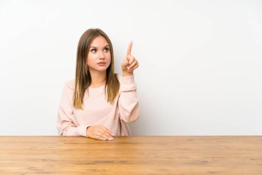 Masadaki genç kız şeffaf ekranda dokunuyor.