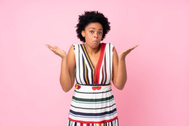 Afro-Amerikalı kadın pembe arka planda şüpheli hareketler yapıyor.