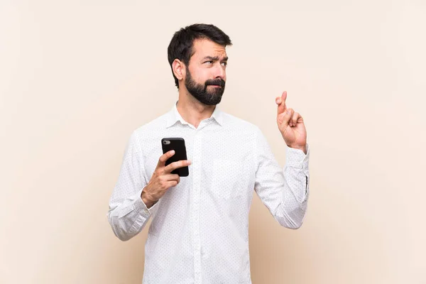 Ung Man Med Skägg Håller Mobil Med Fingrar Korsning Och — Stockfoto