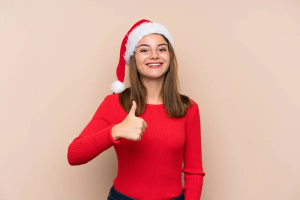 一个戴着圣诞礼帽 背负孤立无援背景的小女孩举起了一个大拇指 — 图库照片