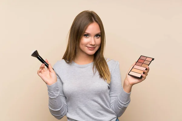 Chica adolescente con paleta de maquillaje sobre fondo aislado — Foto de Stock