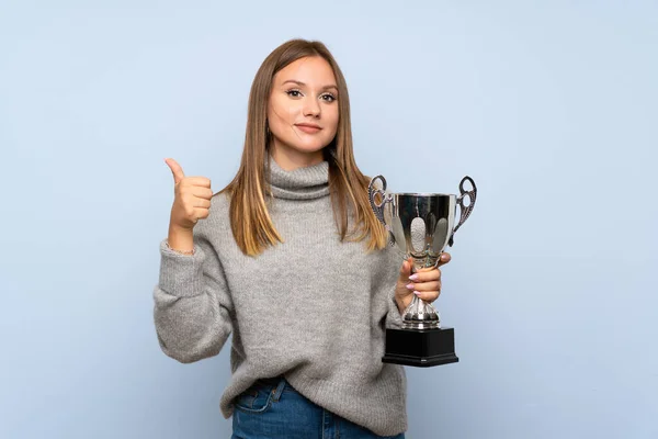 Menina Adolescente Com Suéter Sobre Fundo Azul Isolado Segurando Troféu — Fotografia de Stock