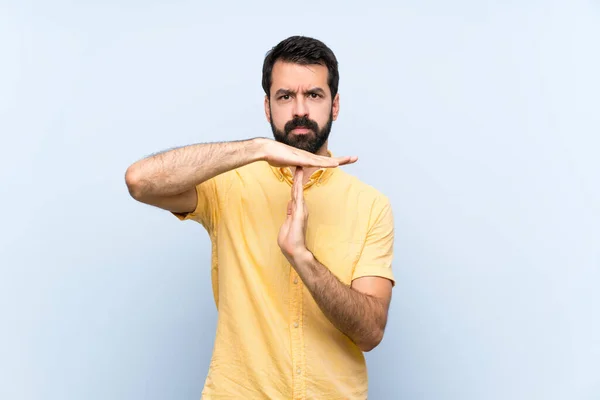 Joven Con Barba Sobre Fondo Azul Aislado Haciendo Gesto Tiempo —  Fotos de Stock