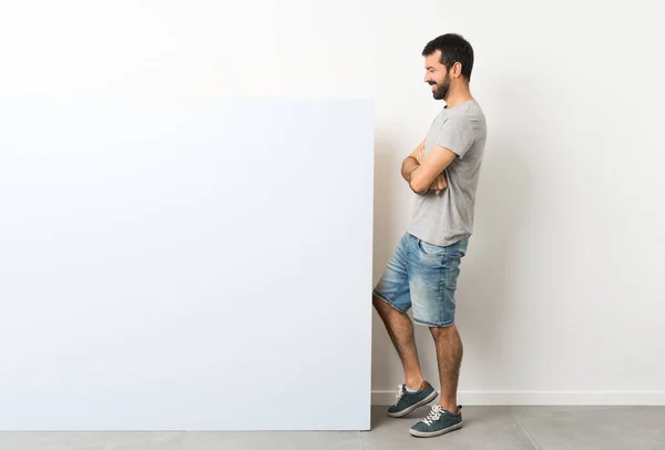 Jovem Homem Bonito Com Barba Segurando Grande Cartaz Azul Vazio — Fotografia de Stock