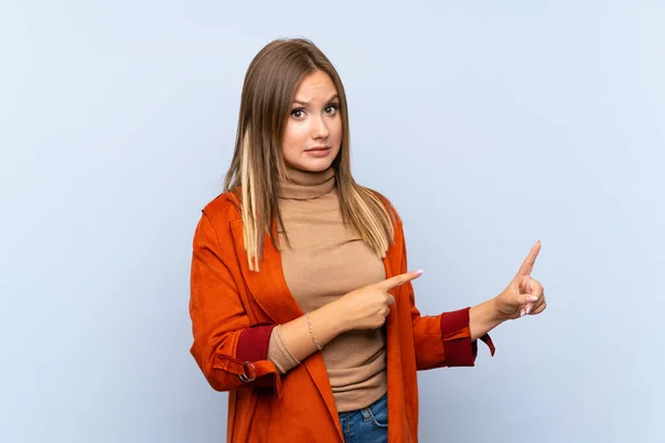 Ragazza Adolescente Con Cappotto Sfondo Blu Isolato Spaventato Indicando Lato — Foto Stock