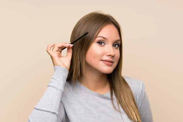 Menina adolescente aplicando rímel com pressa cosmética sobre fundo isolado — Fotografia de Stock