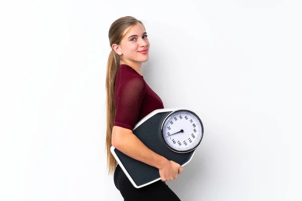 Teenager girl with weighing machine over isolated white background with weighing machine