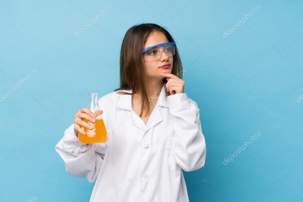 Young brunette girl over isolated blue background with a scientific test tube