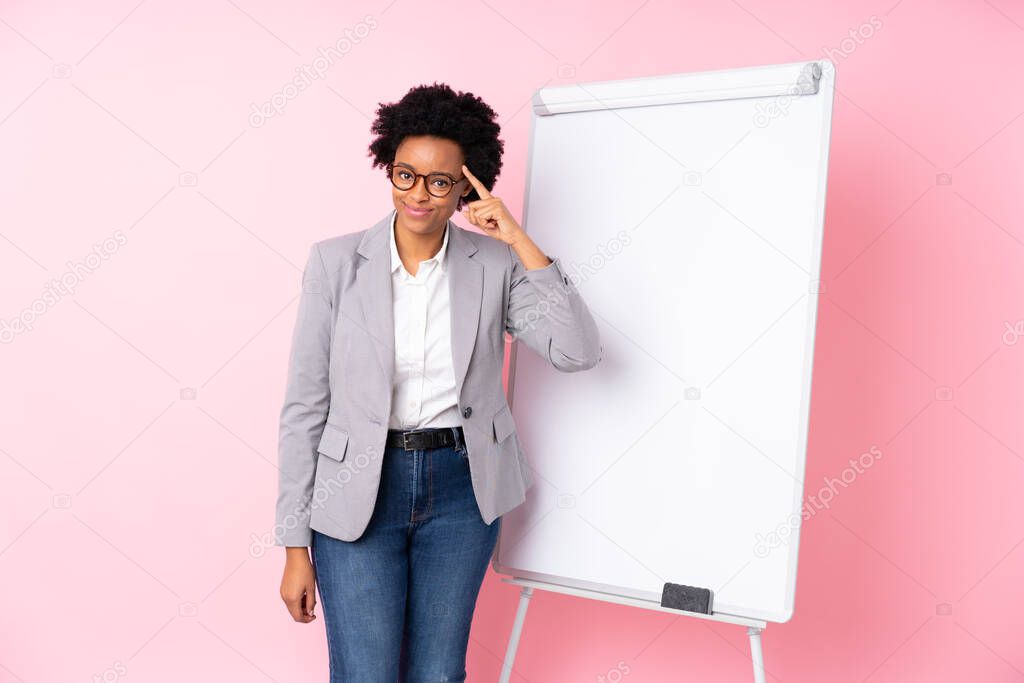 African american business woman giving a presentation on white board over isolated pink background intending to realizes the solution