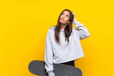 Young skater woman over isolated yellow background having doubts and with confuse face expression