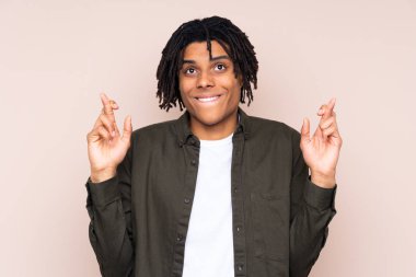 Young African American man over isolated background with fingers crossing and wishing the best