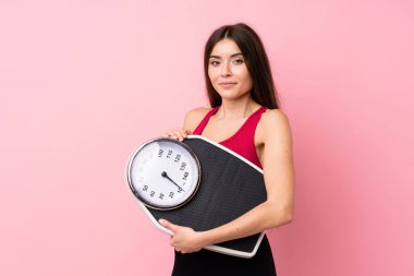 Tartı makinesi ile izole edilmiş pembe arka planda tartı makinesiyle güzel bir genç kız.