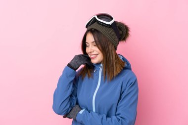 Genç kayakçı kadın pembe arka planda gülüyor.